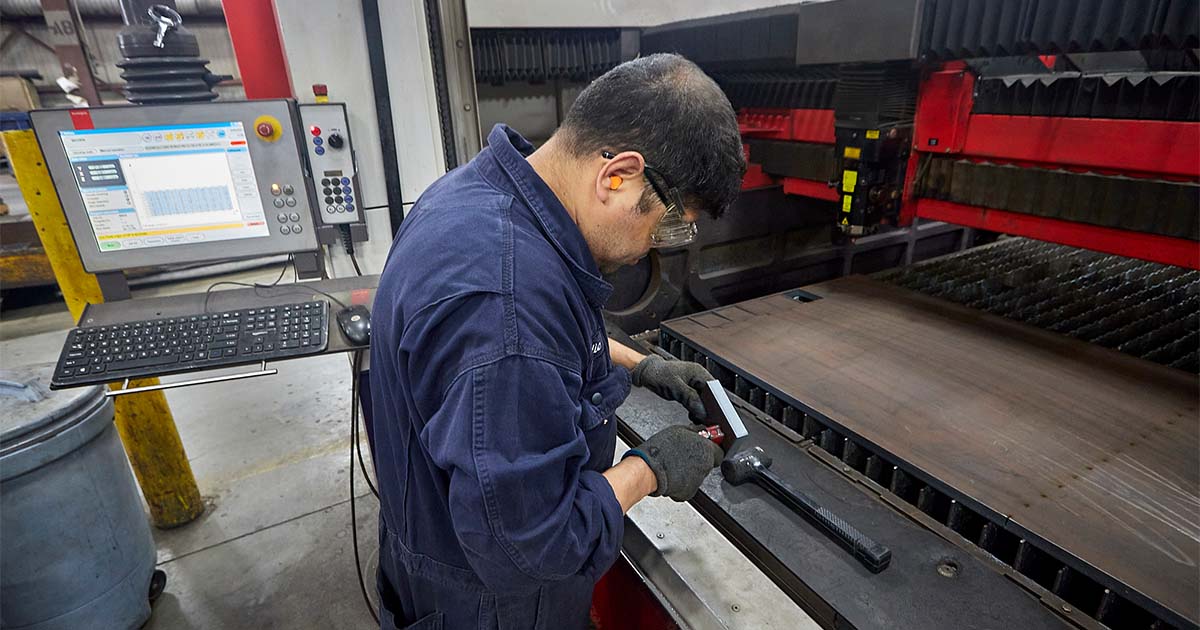 amber steel employee handling metal material near machinery 